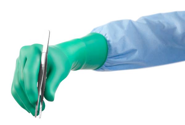 Хирургические перчатки полихлоропреновые зеленого цвета надета на руку в которой находится пинцет.